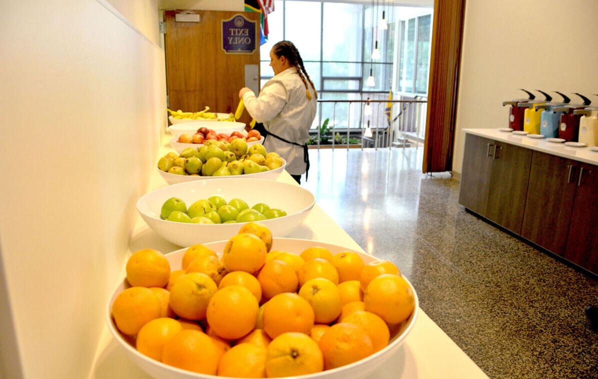 A dining hall worker prepares bowls of fruit